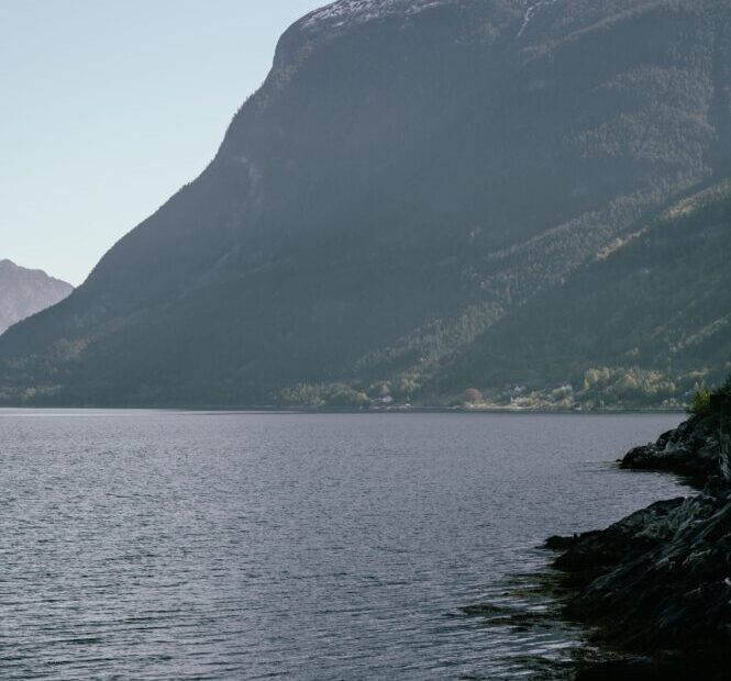 Norvegijos fjordų panorama su kalnais ir tyliu vandeniu